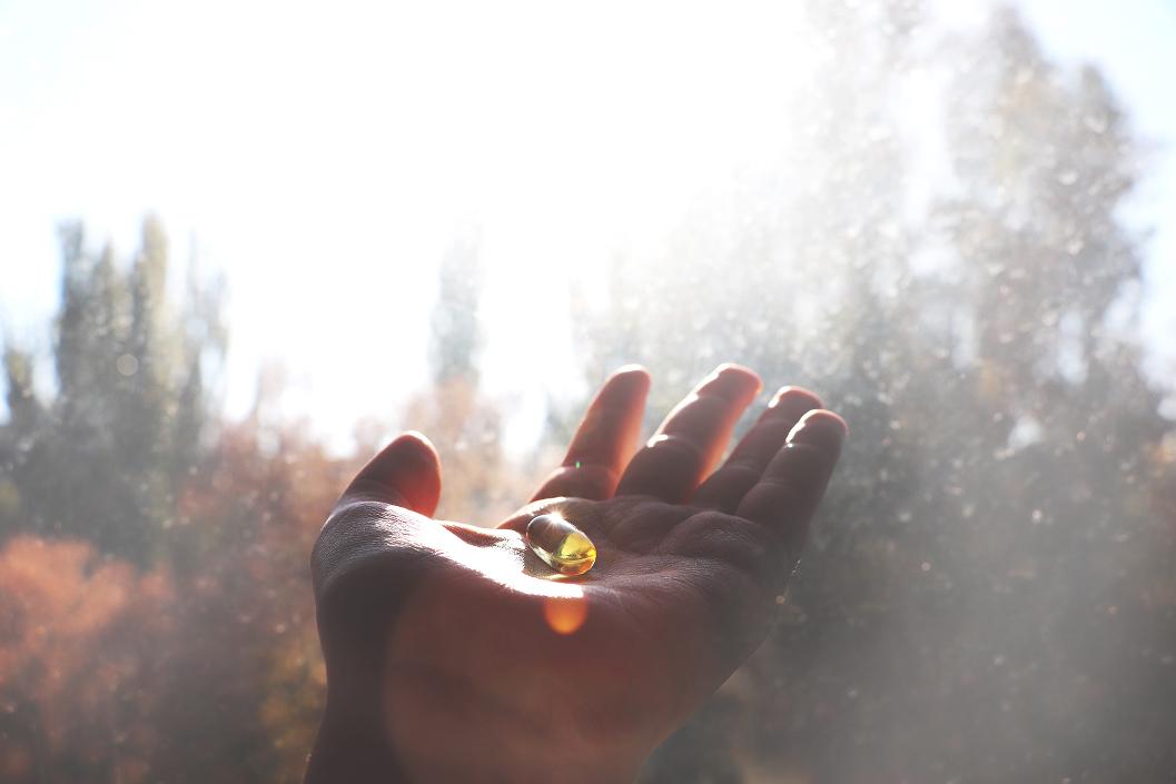 An open hand holding a golden amber stone with a misty forest of evergreen trees in the soft-focused background.
